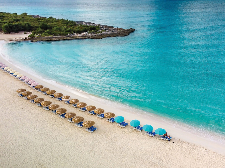 Aerial view of Mullet Beach with loungers and thatched blue umbrellas on white sand near The Morgan Resort Spa Village