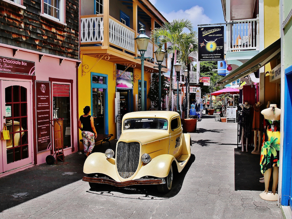 Yellow vintage car parked on a colorful shopping street in Philipsburg near The Morgan Resort Spa Village