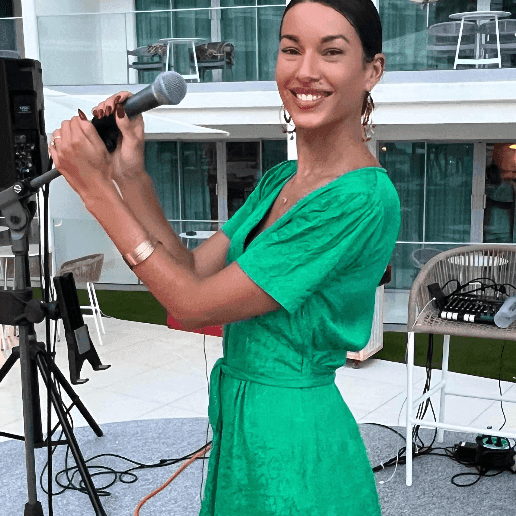 Female singer in a green dress performing on stage with a microphone at The Morgan Resort Spa Village